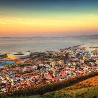  Aerial view of Cape Town at sunset featuring Cape Town Stadium, V&A Waterfront, and the Atlantic Ocean